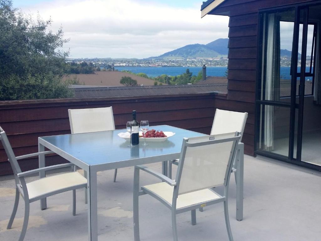 a table and chairs with a bowl of fruit on a patio at Acacia Views - Acacia Bay Holiday Home in Taupo