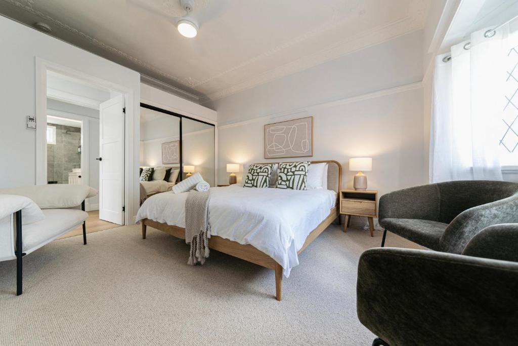 a white bedroom with a bed and a chair at Urban Getaway Bardon Luxe 3 bed 2 bath and pool in Brisbane
