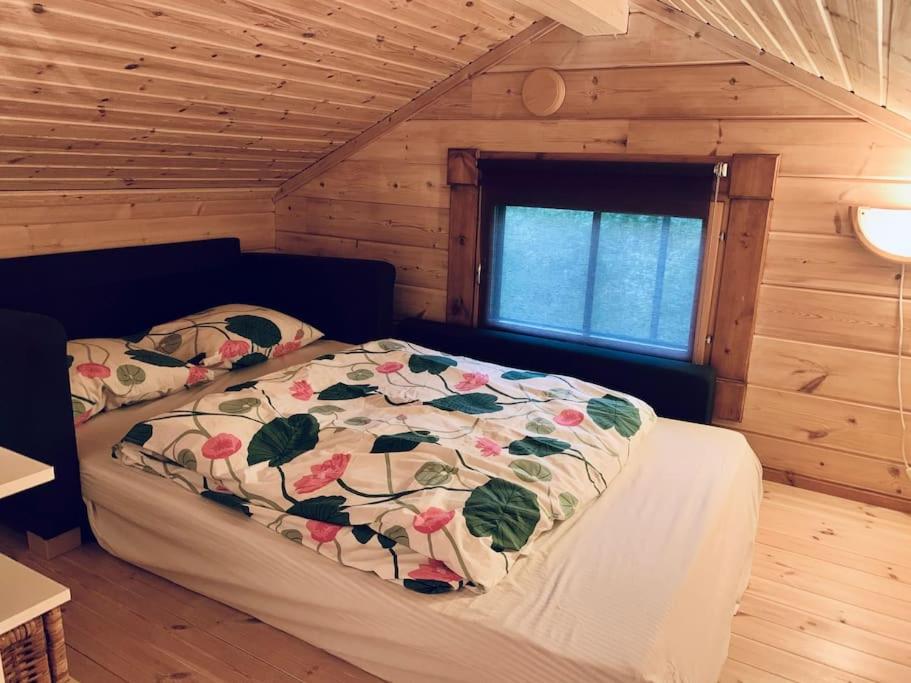 a bedroom with a bed in a log cabin at Fabulous Villa with beautiful lake views in Huutotöyry