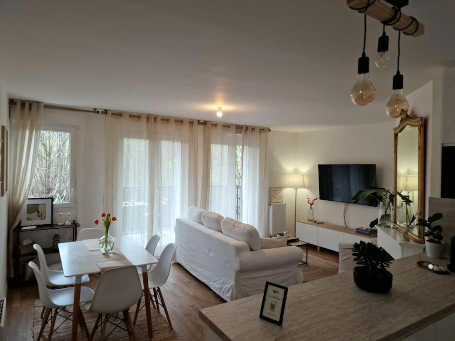 ein Wohnzimmer mit einem weißen Sofa und einem Tisch in der Unterkunft Cozy apartment near Paris in Clamart