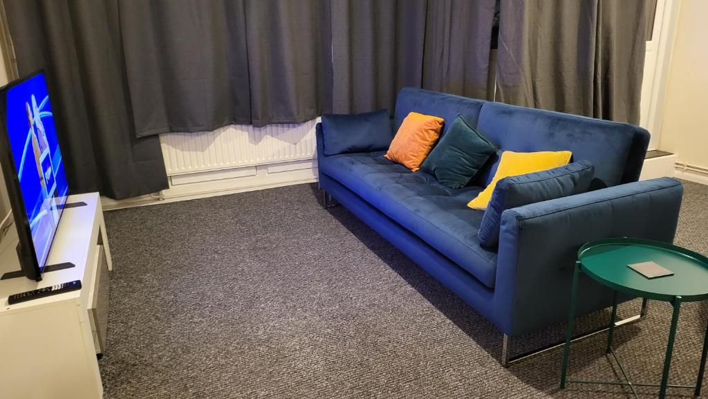 un sofá azul con almohadas coloridas en la sala de estar. en Garland Modern Spacious Flat, London, en Londres