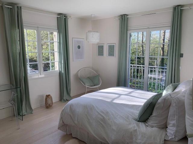 a bedroom with a bed and windows and a chair at Parenthèse Buc'olique in Buc