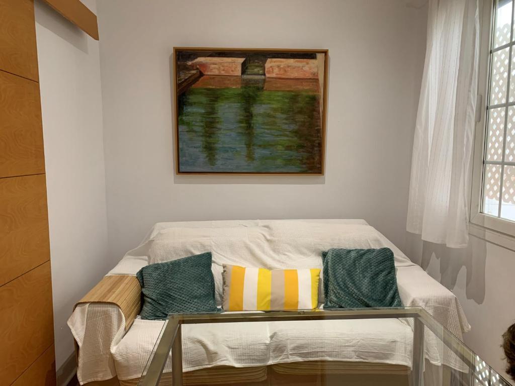 Habitación con sofá y almohadas. en Bonito y tranquilo apartamento en Nervión, en Sevilla