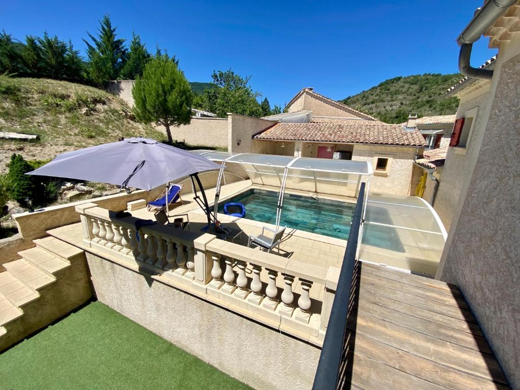 un patio con sombrilla y piscina en Villa Coccinella, en Les Omergues