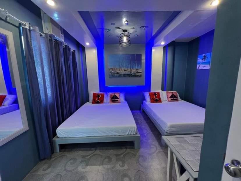 two beds in a room with blue lighting at Country Home Resort in Oslob