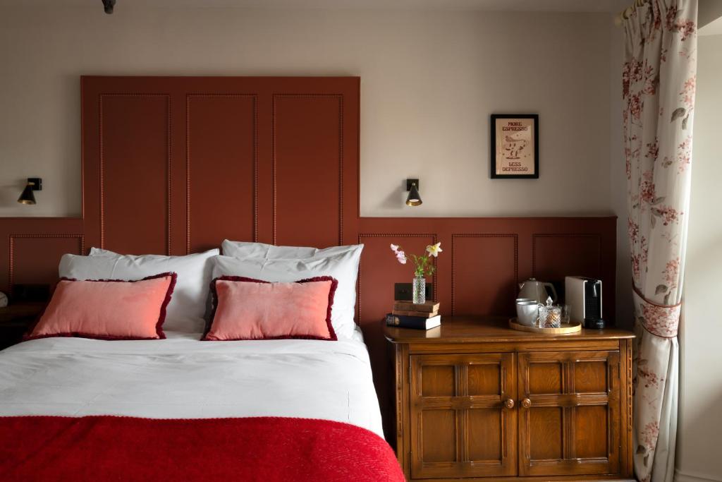 a bed with a red headboard and two red pillows at The Penn in Windermere