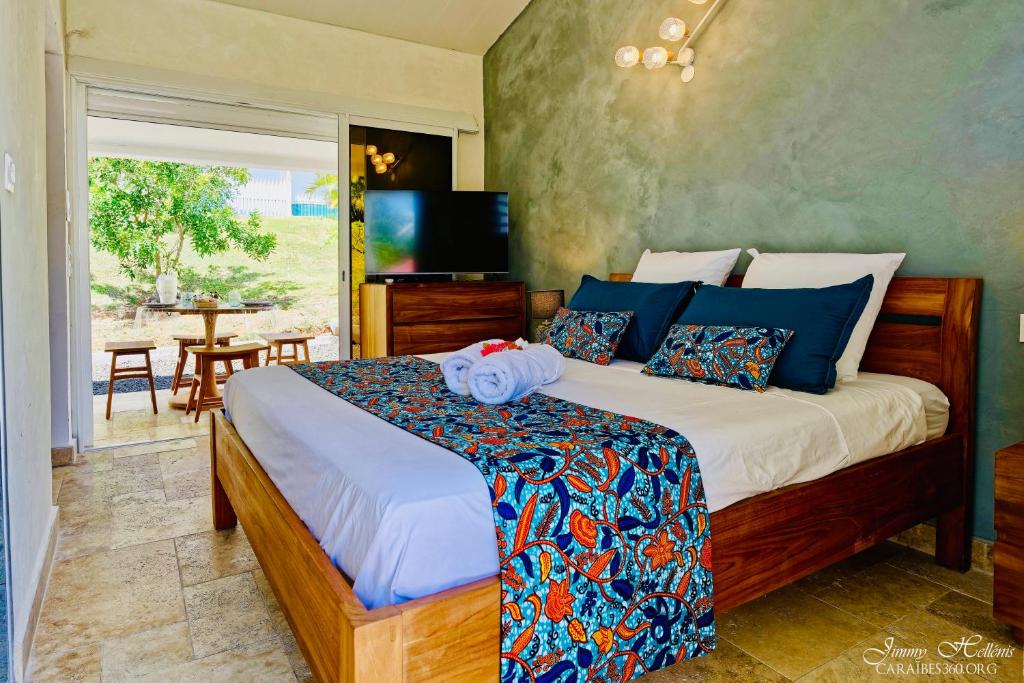 ein Schlafzimmer mit einem Bett und eine Terrasse mit einem Tisch in der Unterkunft Appart T2 Village du Diamant - Cosy et accès plage in Le Diamant