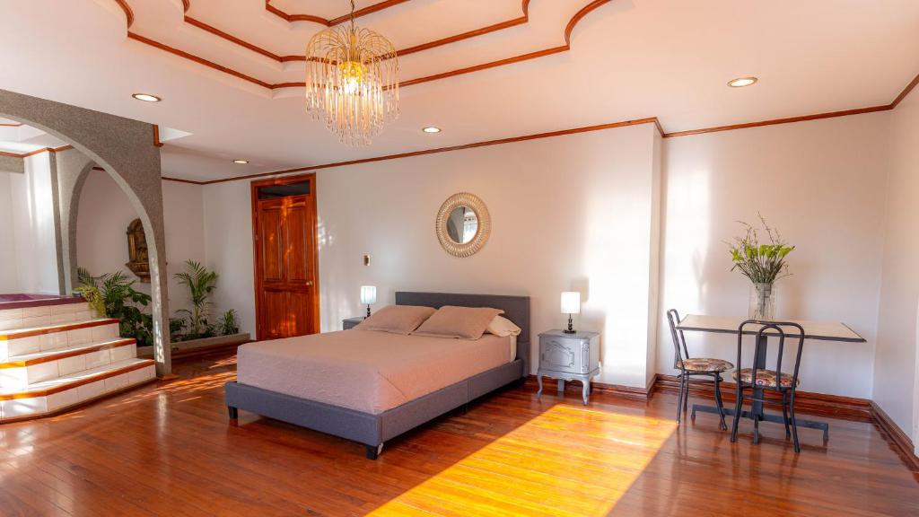 1 dormitorio con cama, mesa y lámpara de araña en Casa Familiar la Tortuga, en Heredia