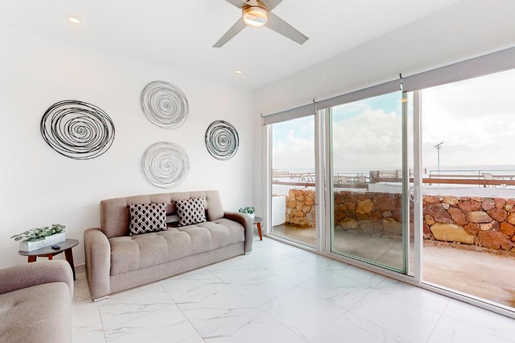 a living room with a couch and a ceiling fan at Casa Platino 22 - Playa Arcangel in Rosarito