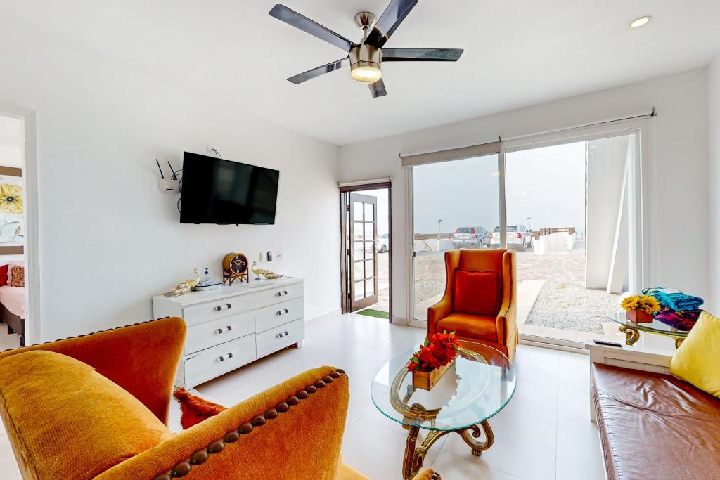a living room with two chairs and a tv at Casa Merlot 41 - Playa Arcangel in Rosarito