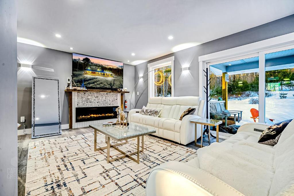 a living room with white furniture and a fireplace at Luxury Spa Chalet in Greenwood