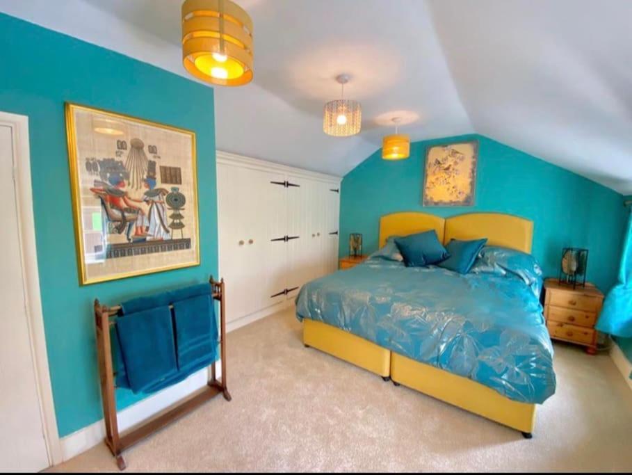ein blaues Schlafzimmer mit einem großen Bett darin in der Unterkunft Traveller's Rest - Cosy cottage in heart of Wilton in Salisbury
