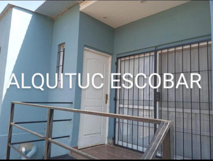un edificio azul con puerta blanca y balcón en ALQUITUC ESCOBAR II en Belén de Escobar