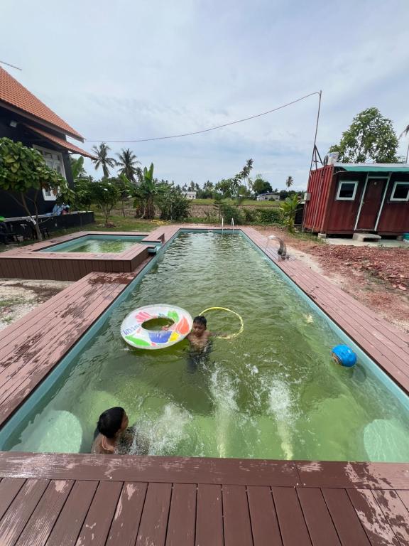 duas crianças a brincar com um frisbee numa piscina em HOMESTAY Kampong KOTA AUR Resort with swimming pool, Kepala Batas, SEBERANG PERAI, PENANG -MOTAC registered Awarded ASEAN homestay standard Malaysia AWARD 2023-2025 Only 3 minutes from viral KG AGONG em Kepala Batas