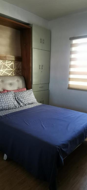 a bedroom with a blue bed with a window at Mesaverte Residences "ZACE STUDIO" in Cagayan de Oro