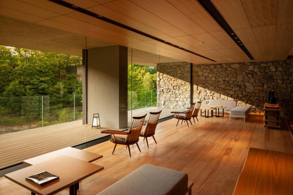 a living room with a stone wall and tables and chairs at Chalet Ivy Jozankei in Jozankei