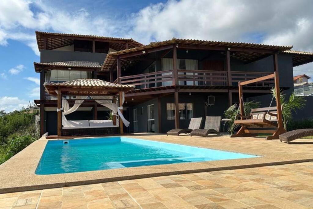 a house with a swimming pool in front of a house at 6 Suites, banheira, Piscina, no coração da Região dos Lagos in São Pedro da Aldeia