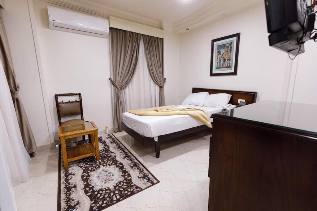 a bedroom with a bed and a table and a television at Badr Hotel Assiut in Asyut