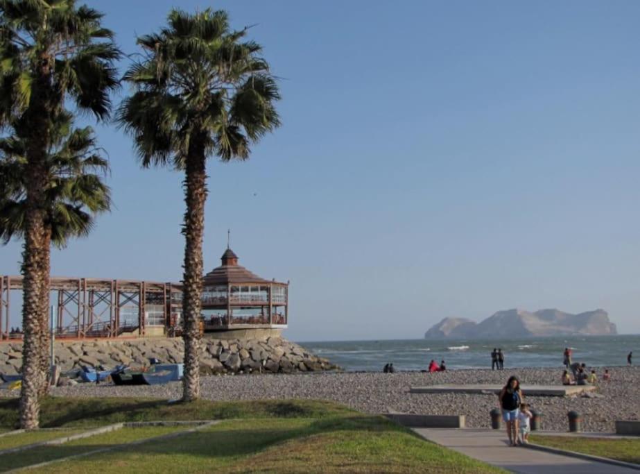 a beach with palm trees and a building on it at Modern Apartment close to the airport in Lima