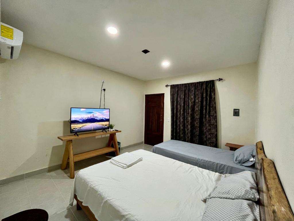 um quarto de hotel com duas camas e uma televisão em Posada Ceibamar Chichen Itzá em Pisté