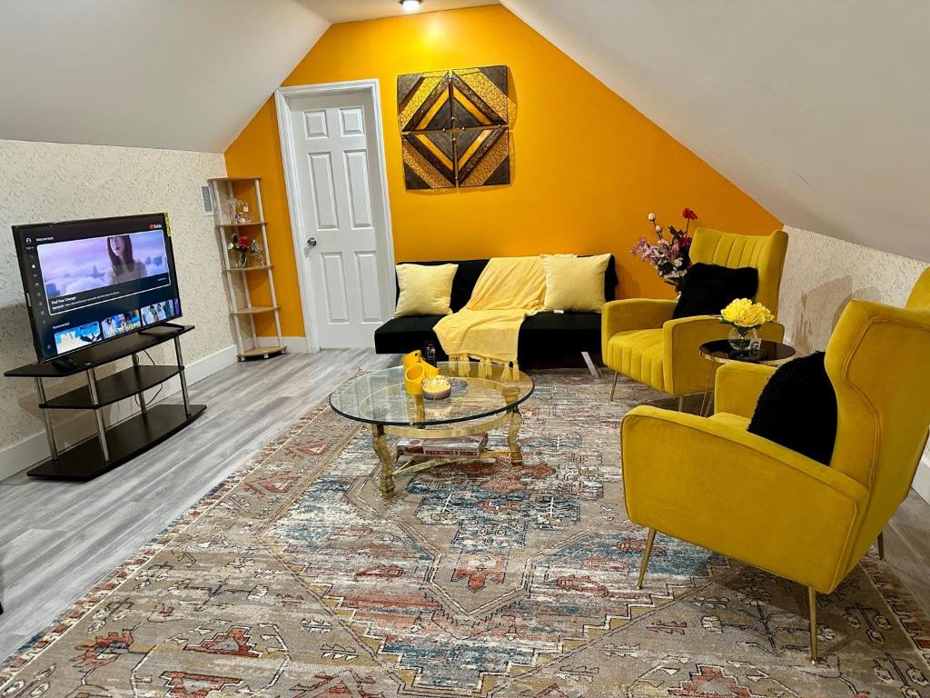 Elle comprend un salon doté d'un mobilier jaune et d'une télévision. dans l'établissement Skylife Home away from home, à Irvington
