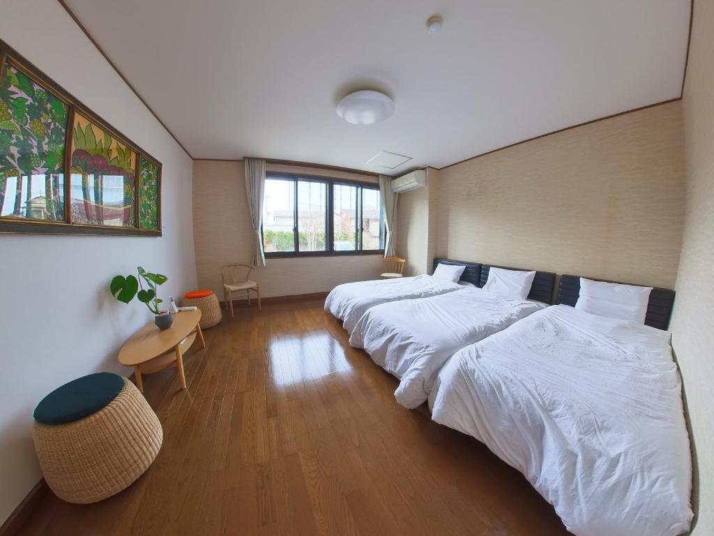 a bedroom with two beds and a table and a window at TSURUOKA GINZA 朙 sukima in Tsuruoka