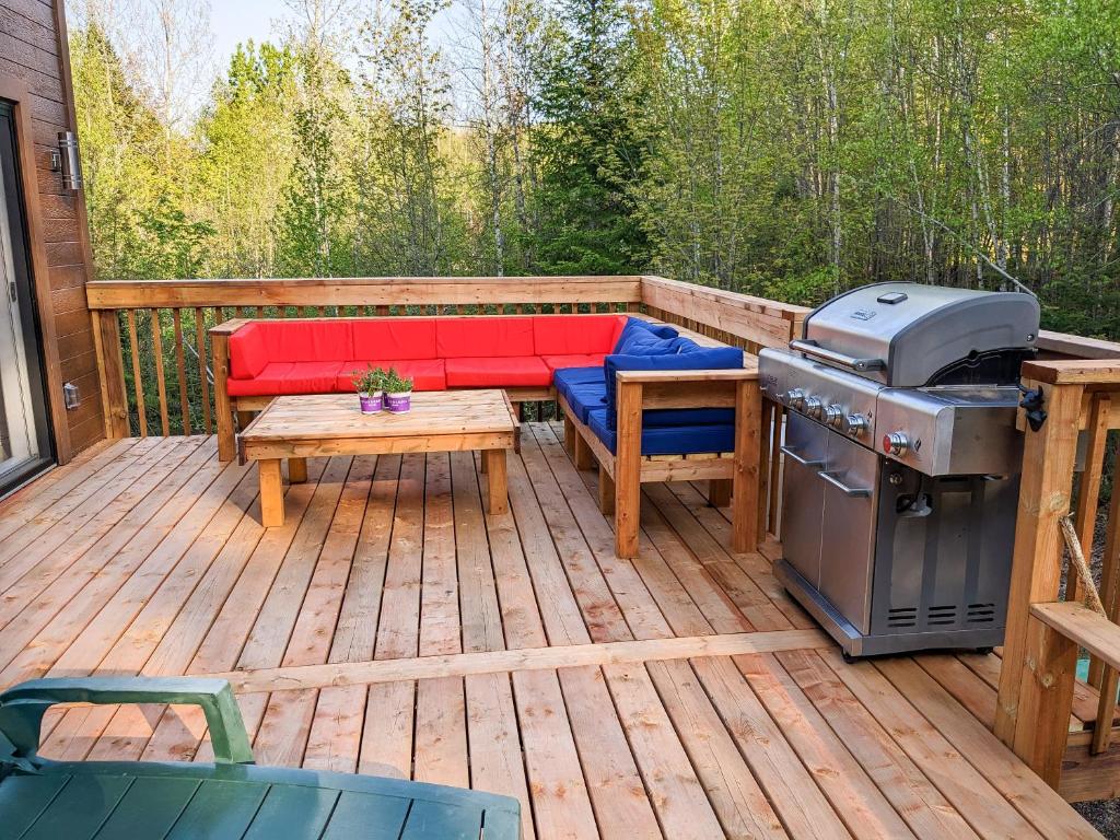 a patio with a bench and a grill on a deck at L'hêtre au Sommet (gîte) in Sainte Anne des Lacs