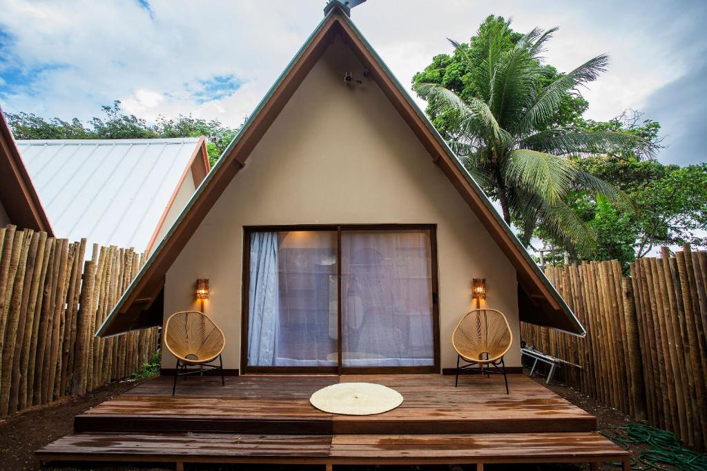 a small house with two chairs on a wooden deck at Cabana Pitomba - Viagem Inspirada in Fernando de Noronha
