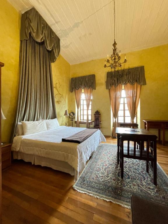 a bedroom with a bed and a table and windows at NASS Casa del Aguila in Cuenca