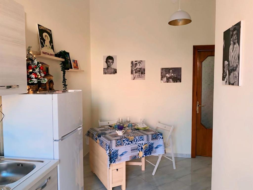 a kitchen with a table and a white refrigerator at Casetta Sofia in Pozzuoli