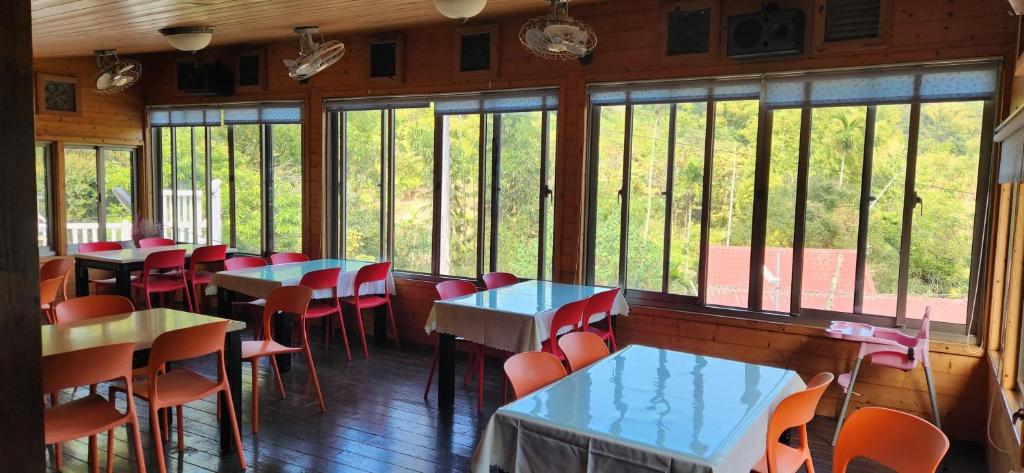 a dining room with tables and chairs and windows at Ji Ji Farm Homestay in Jiji