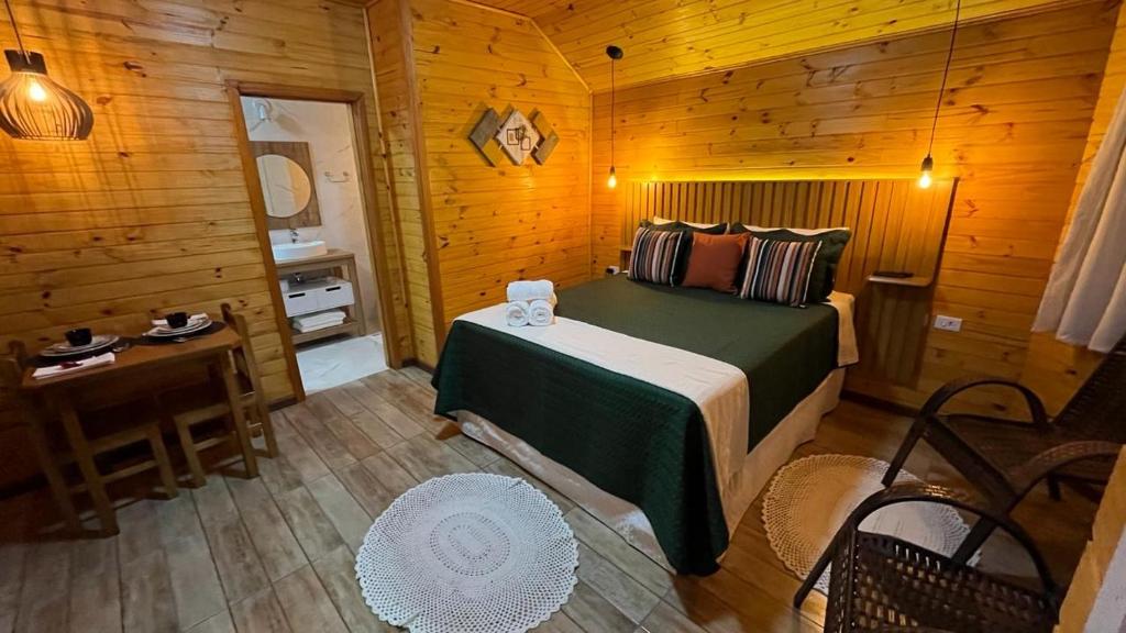 een slaapkamer met een bed in een houten hut bij Chalés Canto da Serra in Monte Verde