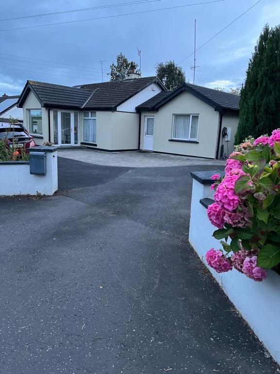 a house with pink flowers on a driveway at Kilmactrasna Cottage in Carrickmacross