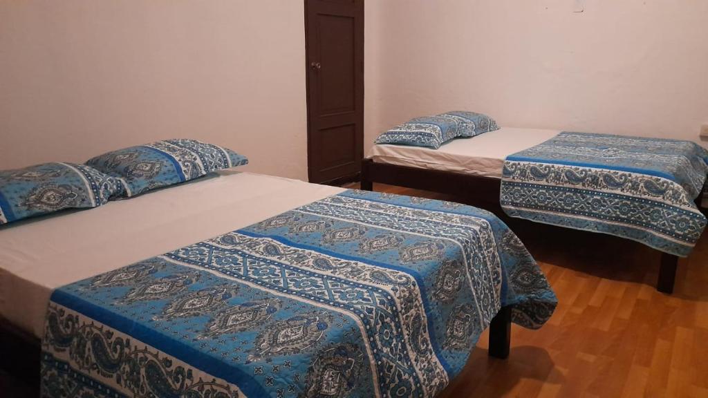 een kamer met drie bedden met blauwe en witte dekens bij Hotel Sansivar in El Venado