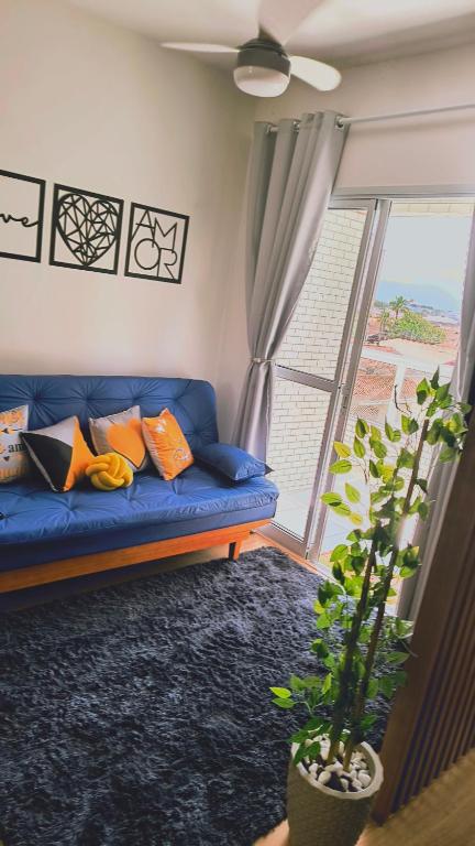 - un canapé bleu dans le salon doté d'une fenêtre dans l'établissement Cantinho Sol & Mar Pé na Areia frente ao Mar com churrasqueira na sacada e piscina, à Praia Grande