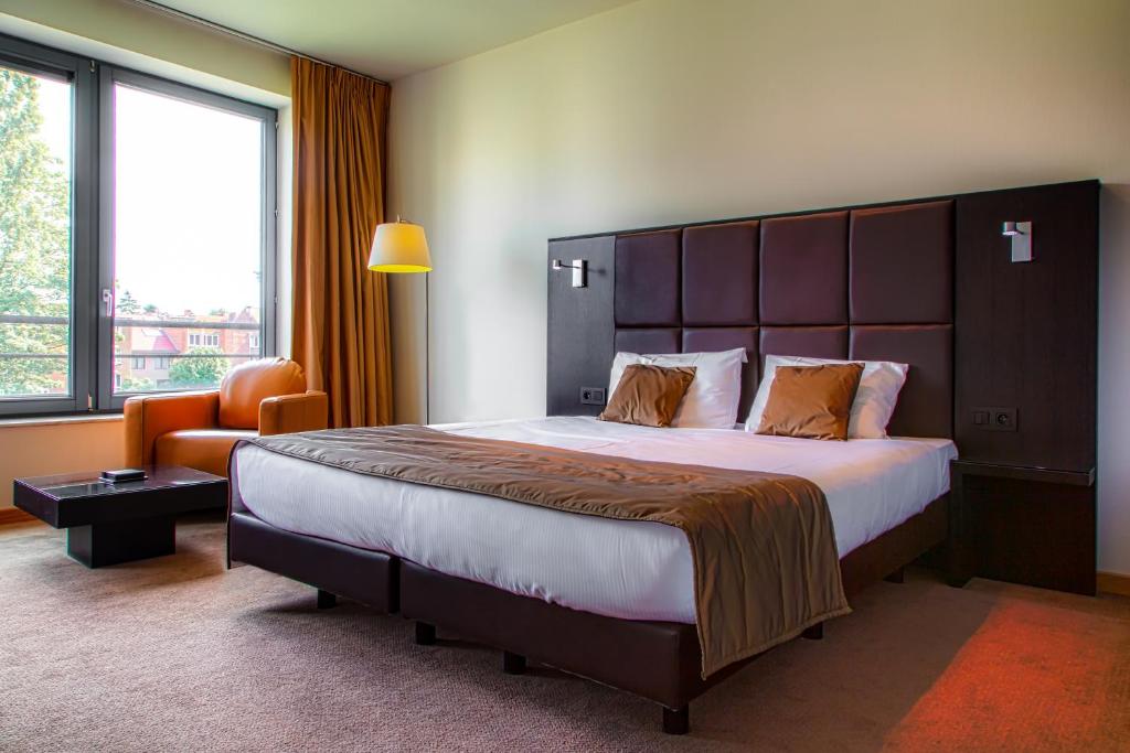 ein Hotelzimmer mit einem großen Bett und einem Stuhl in der Unterkunft Diamant Suites Brussels EU in Brüssel