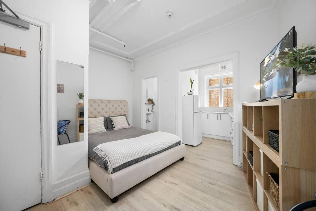 a white bedroom with a bed and a tv at Urban retreat in Potts Point in Sydney