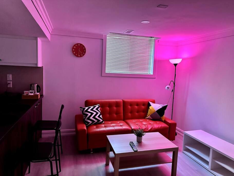 - un salon avec un canapé rouge et un mur rose dans l'établissement Fully furnished unit in Northyork!, à Toronto