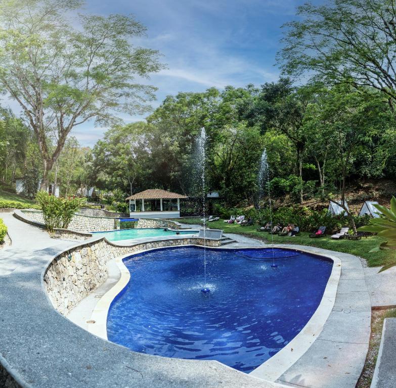 a swimming pool with a fountain in a yard at Hotel Kopal in Lanquín