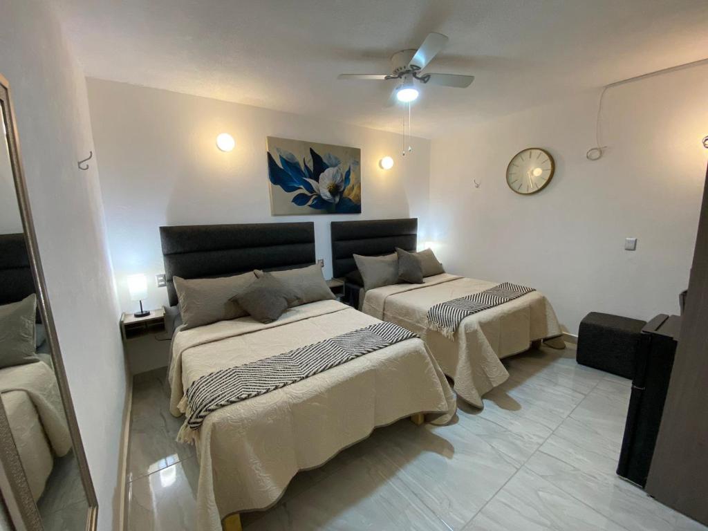 um quarto com duas camas e um relógio na parede em Hotel Posada Jardín Aguascalientes em Aguascalientes