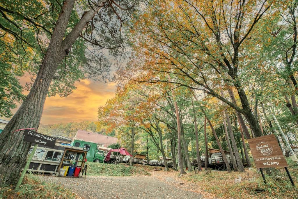 a dirt road in the woods with a sign and trees at Nagano GLAMPINGBASE enCamp in Shiojiri