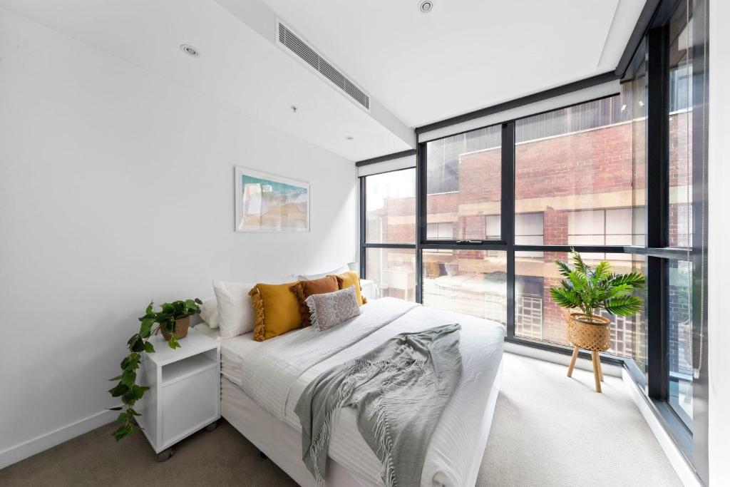 - une chambre avec un lit et une grande fenêtre dans l'établissement A Chic & Comfy 2BR Apt Near Federation Square, à Melbourne