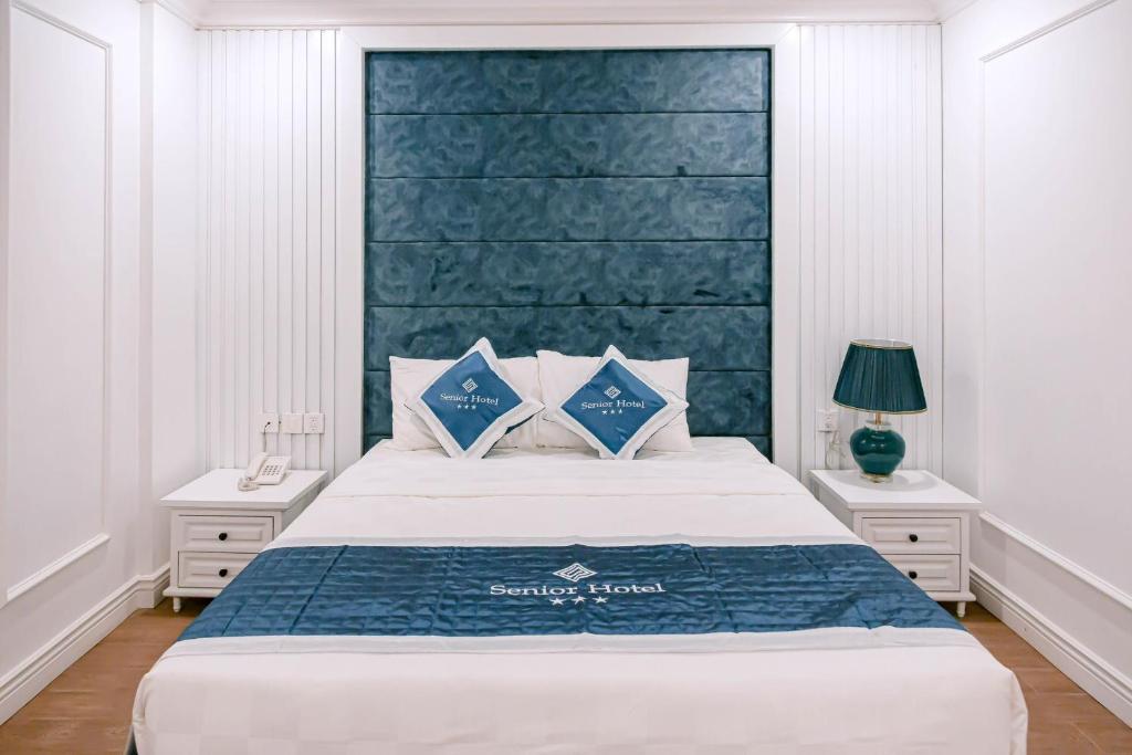 a bedroom with a large bed with a blue headboard at Senior Hotel in Can Tho