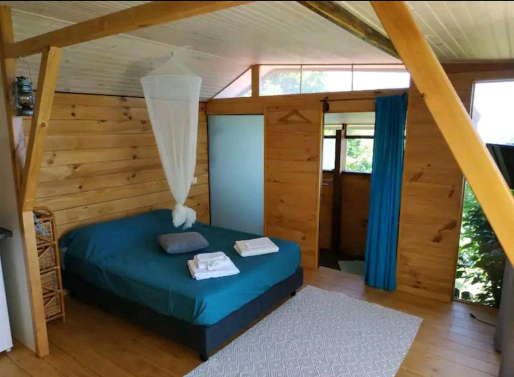ein Schlafzimmer mit einem blauen Bett in einem Zimmer mit Holzwänden in der Unterkunft Bungalow Moemoea in Punaauia