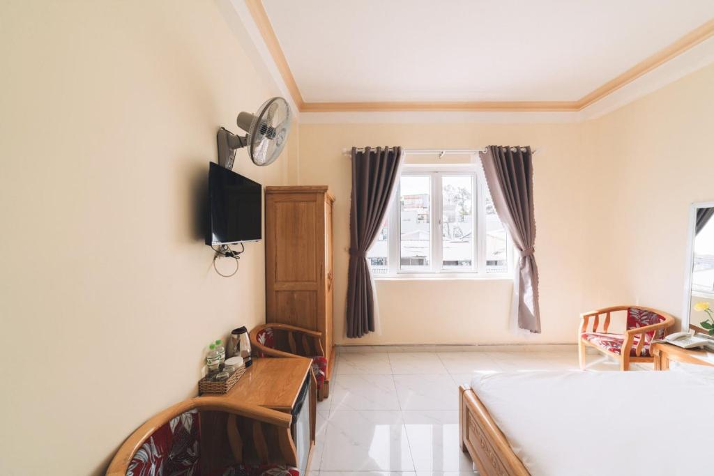 1 dormitorio con 1 cama, TV y ventana en KHÁCH SẠN TUẤN KIỆT en Dalat