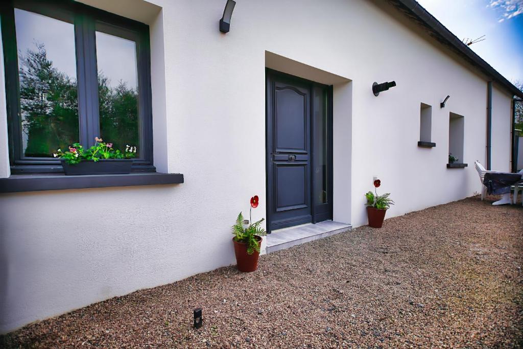 a white house with potted plants on the side of it at charmante Maison de campagne 