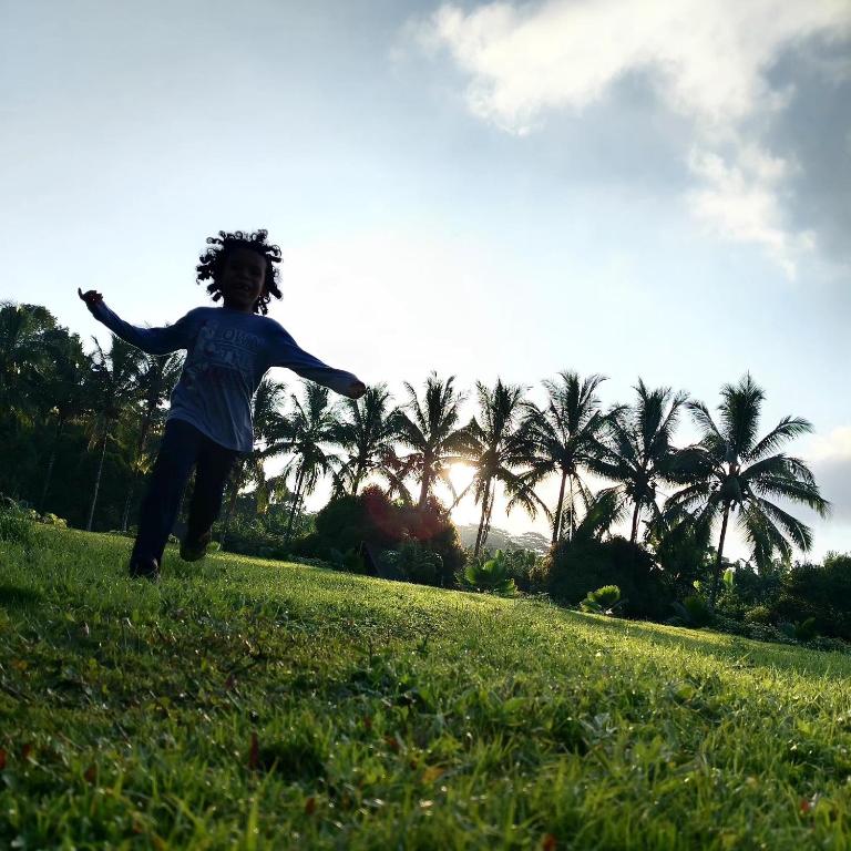 a young child jumping in a field with a frisbee at Campo Duro Ecolodge in Puerto Villamil