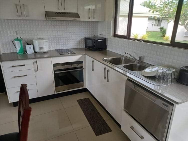a kitchen with white cabinets and a sink and a stove at Bula Villas in Nadi
