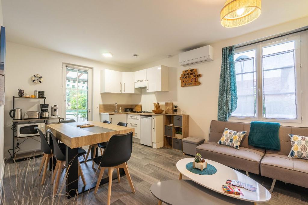 ein Wohnzimmer mit einer Couch, einem Tisch und einer Küche in der Unterkunft Maison de vacances centre ville in Ronce-les-Bains