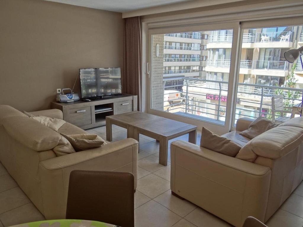ein Wohnzimmer mit 2 Sofas, einem Tisch und einem Fenster in der Unterkunft Helios 0201 with central location in Nieuwpoort